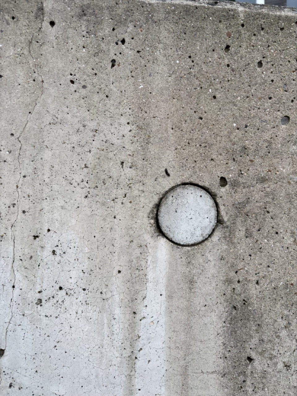 Photograph of concrete wall with circular cut out, rough surface